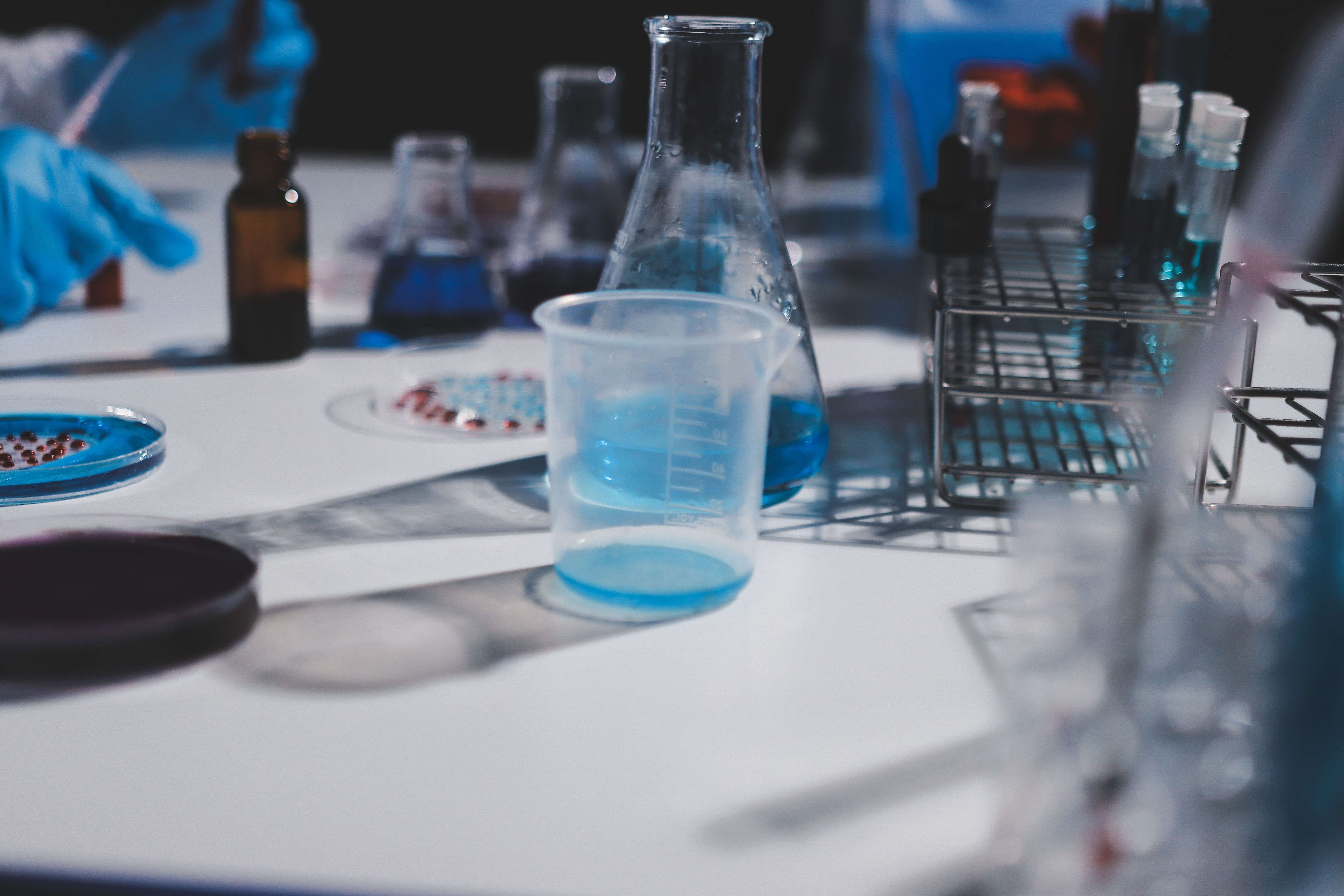 Blue nitrile gloves protecting hands from chemical splash during laboratory cleaning task.